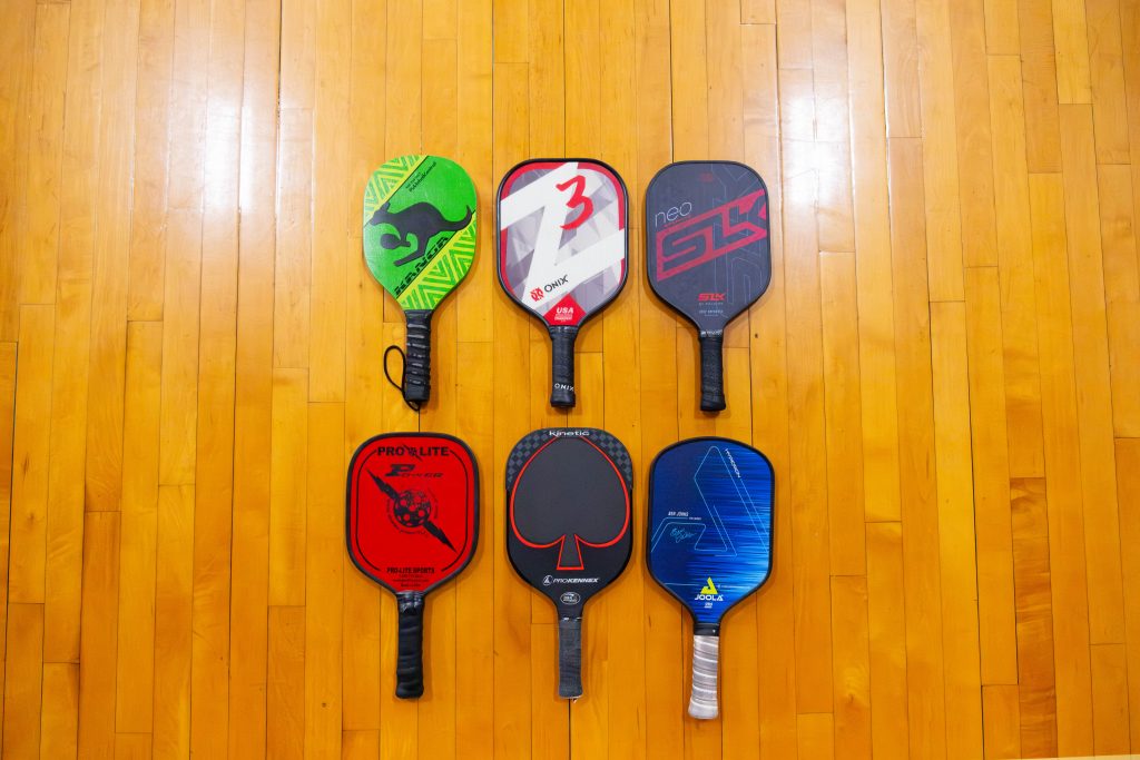 Image shoes 6 different paddles. The paddles are various lengths and widths to show the diverse options players have when choosing a paddle.