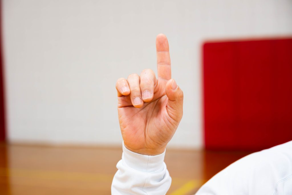 Man holding index finger up to signal out call.