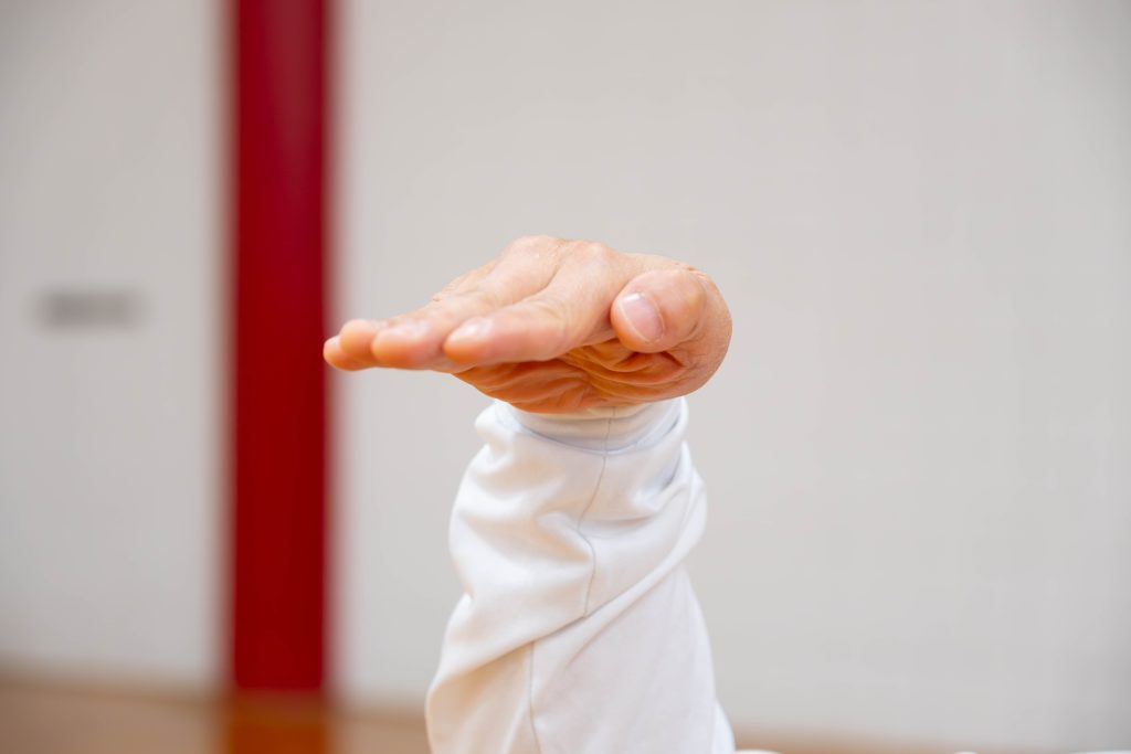 Man with a hand gesture keep all fingers together and hand flat with the palm down.